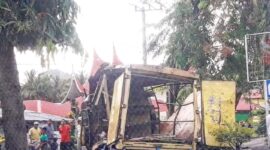Satu unit mobil box berwarna kuning usai bagian atas mobil menabrak pohon.