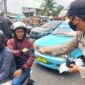 Petugas saat membagikan masker kepada pengendara 