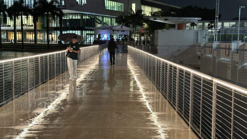 <p> Foto file: Mahasiswa Universitas Miami membuka payung di jembatan Danau Osceola Kamis malam, 18 September 2025.
<p> <span class=